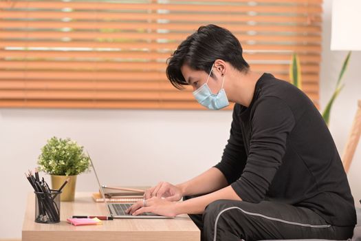 Asian man using computer tablet in living room.