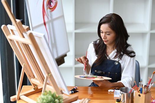 Young woman painting picture with water color at her art workshop.