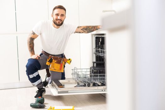 Technician or plumber repairing the dishwasher in a household.