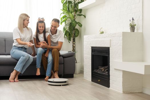 Family resting while robotic vacuum cleaner doing its work at home.