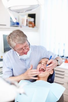 Check up visit. Portrait of male dentist checking patients teeth