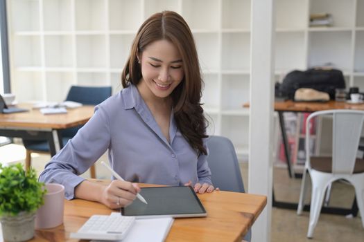 Smiling businesswoman working with digital tablet in modern workplace.