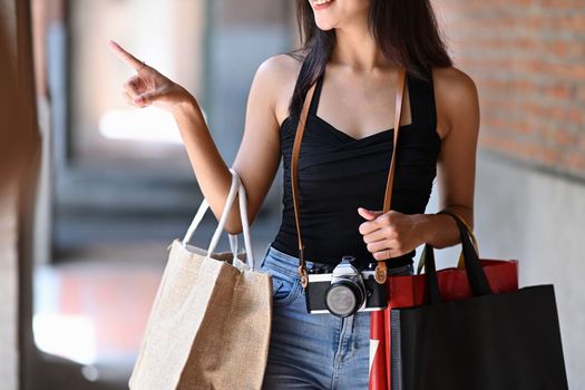 Young woman traveler carrying shopping bags and working at shopping mall.