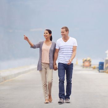 Look at that. Full length shot of a young couple looking at the views while walking next to the beach