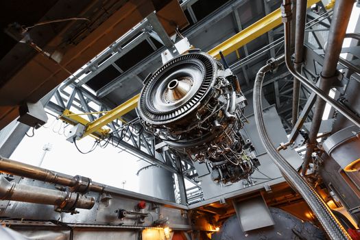 The engine of a gas turbine compressor hangs on a crane during installation in a module for generating electricity