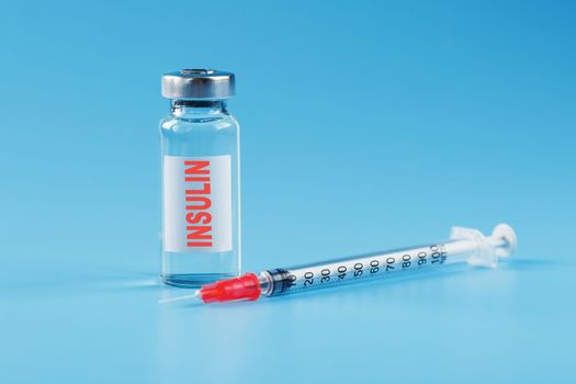 A bottle of insulin hormone and a syringe on the table on a blue background