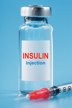 A bottle of insulin hormone and a syringe on the table on a blue background