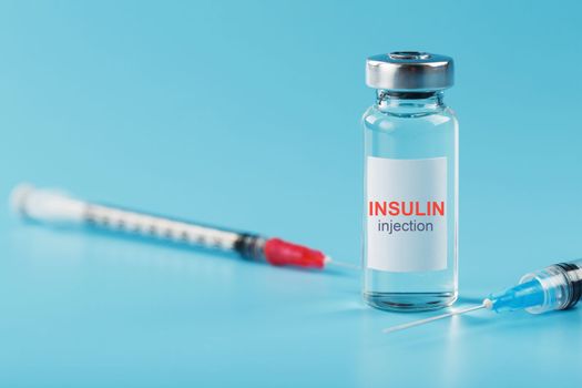 A bottle of insulin hormone and a syringe on the table on a blue background