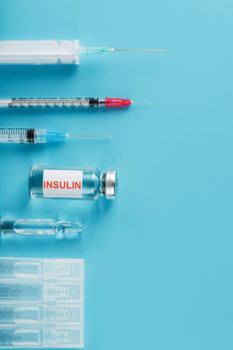 Medicine in ampoules with insulin, needles and syringes for medical subcutaneous injection on a blue background