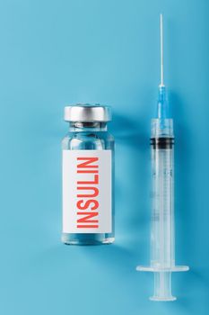 A bottle of insulin hormone and a syringe on the table on a blue background