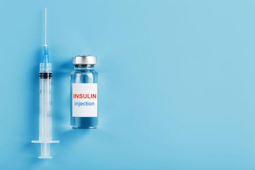 Medicine in ampoules with insulin, needles and syringes for medical subcutaneous injection on a blue background