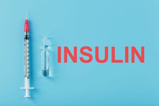 Medicine in ampoules with insulin, needles and syringes for medical subcutaneous injection on a blue background