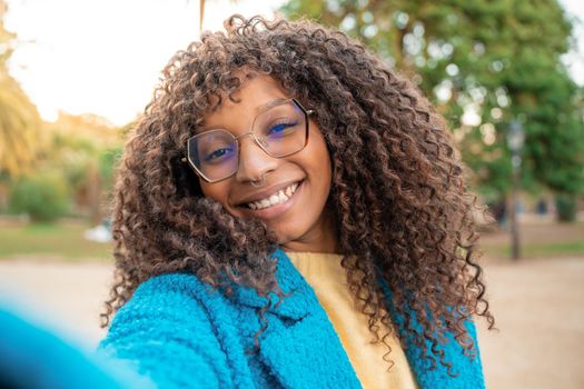 Point of view of an African American woman smiling taking selfie. Positive cheerful trendy girl posing for sharing in social media app. 