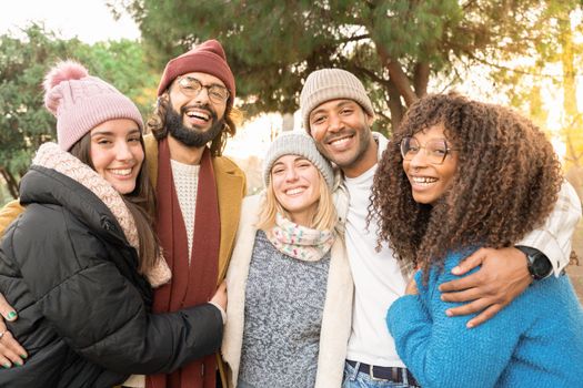 Happy friends from diverse cultures and races taking selfie looking at camera smiling outdoors. Cheerful people having fun. Concept of community and friendship.