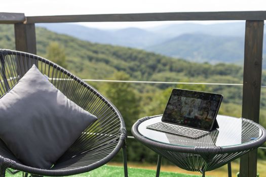 Laptop on terrace with white screen and mountains blurred as a background