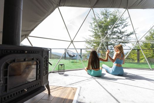 mother and daughter yoga in a glamping dome tent.