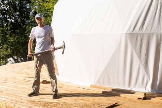 the master builds the dome. Outside spherical glamping dome. Hemispherical structure lattice shell geodesic polyhedron. Camping house hotel party tent