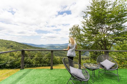 Young beautiful woman on the terrace in the mountains.