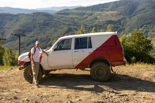 man standing on a mountain view. Young male traveler is enjoying beautiful landscape during road trip on car.