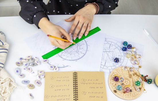 Woman astrologer draws a natal chart. Selective focus. People.