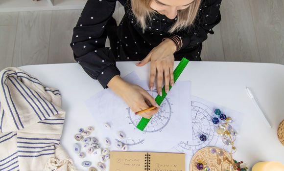 Woman astrologer draws a natal chart. Selective focus. People.