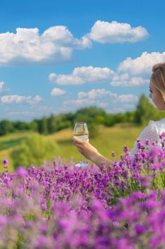 the girl holds a glass of wine on the background of a lavender field. Selective focus. Nature