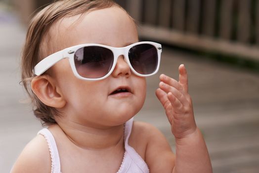 Loving Fashion from a young age. An adorable baby girl wearing oversized sunglasses outside