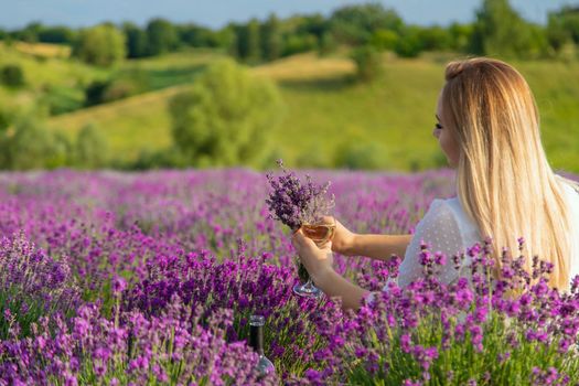 the girl holds a glass of wine on the background of a lavender field. Selective focus. Nature