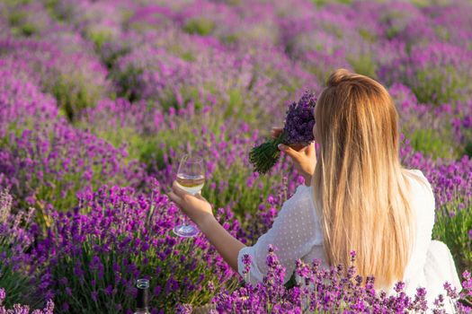the girl holds a glass of wine on the background of a lavender field. Selective focus. Nature