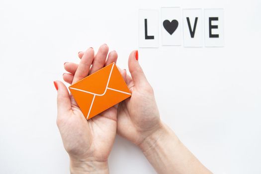 A love letter holding a small wooden orange envelope. Love lettering