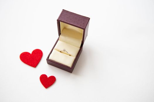 Beautiful red hearts on a white background together with a ring in a box. Marriage proposals