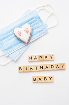 Disposable medical mask and two hearts. Heart with baby footprint. Childbirth in the coronavirus pandemic. Happy birthday lettering