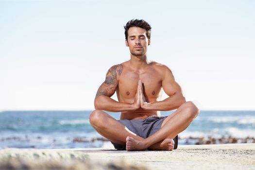 Seeking enlightenment in nature. A young man meditating next to the ocean