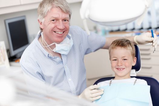 Smiling dentist with child. Portrait of mature dentist smiling with child at clinic