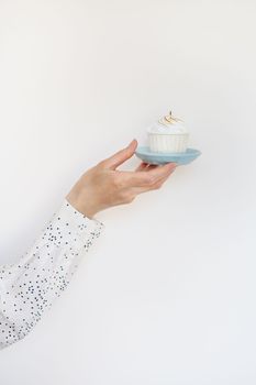 A female hand holds a delicious cupcake, congratulations on a happy birthday. Place for an inscription