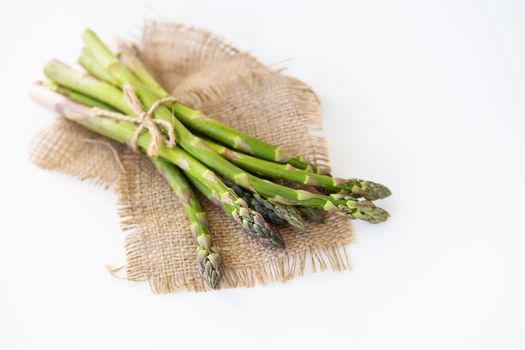 Fresh green asparagus tied with thread and lying on sacking. Healthy and wholesome food concept. View from above