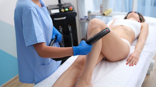 Woman does laser hair removal on legs. High-quality laser epilation of lower leg concept