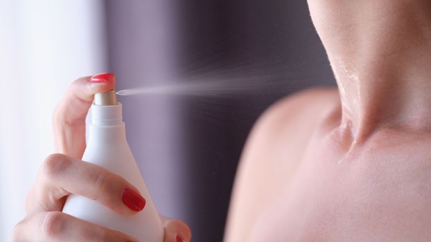 Closeup of woman hand applying fragrance to neck. Perfumed body products concept