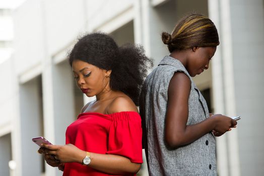 two young smiling women standing back outside and talking on the phone.concept communication and youth