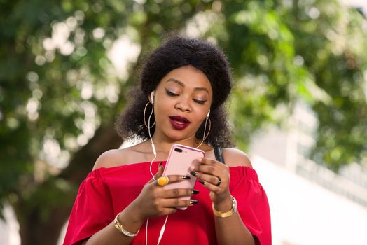 Happy young woman wearing a red t-shirt with headphones talking on the mobile phone in the city