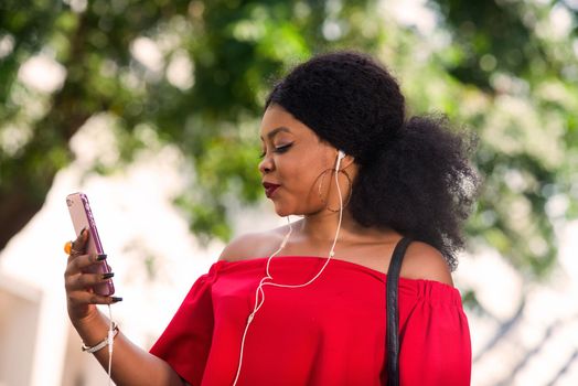 Happy young woman wearing a red t-shirt with headphones talking on the mobile phone in the city