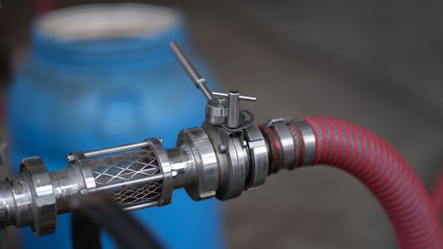Barrels with a tap and a hose for production of beer or wine. Industrial stainless steel pipe equipment with faucet and hose for production