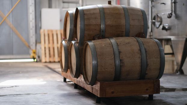 Winery and cognac factory with steel fermentation tanks and wooden barrels for aging process. Food industry and winemaking concept