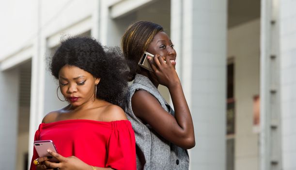 two young smiling women standing back outside and talking on the phone.concept communication and youth