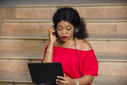 young girl sitting with laptop listening to music using headphones.