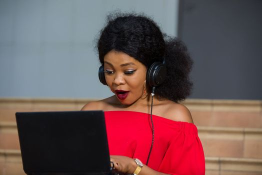 young girl sitting with laptop listening to music using headphones.