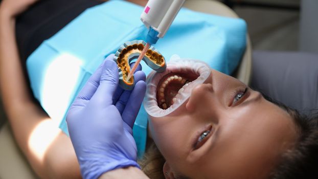 Orthodontist works with shape of jaw cast in process of prosthetics of facial arch of woman. Orthodontic treatment in dentistry prosthetics and veneer installation