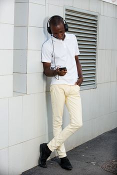 people, music, technology, leisure and lifestyle - Happy african young man with headphones and smart phone on the street