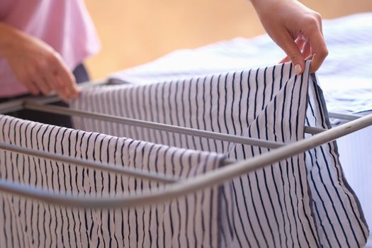 Woman hands hang clothes on dryer at home. Drying wet clothes concept
