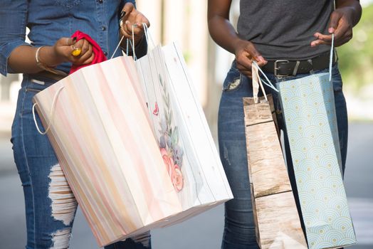two women walking in an urban environment and carrying shopping bags.